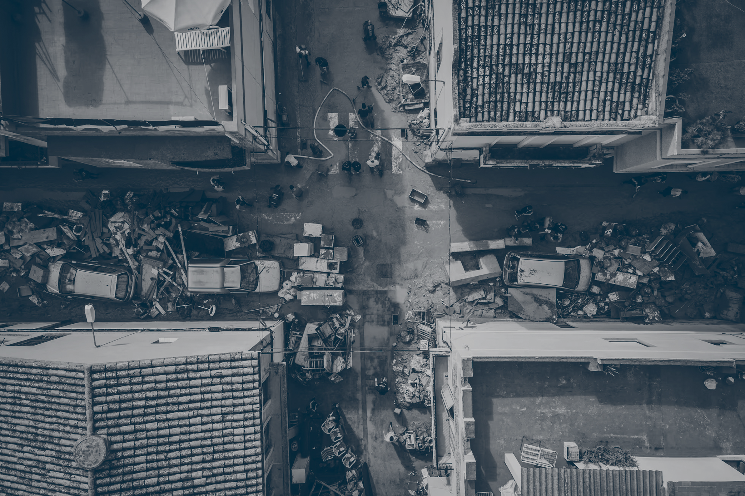 Vista aérea de una calle de Valencia tras la DANA, con vehículos desplazados y enseres apilados en las aceras